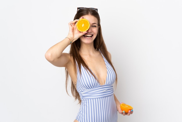 Joven mujer caucásica aislada sobre fondo blanco en traje de baño y sosteniendo una naranja