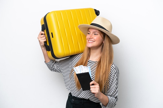 Joven mujer caucásica aislada sobre fondo blanco en vacaciones con maleta y pasaporte