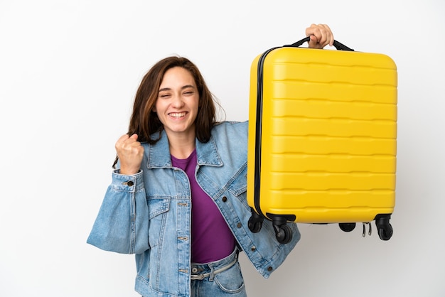 Joven mujer caucásica aislada sobre fondo blanco en vacaciones con maleta de viaje