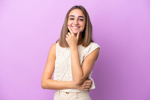 Joven mujer caucásica aislada sobre fondo púrpura feliz y sonriente