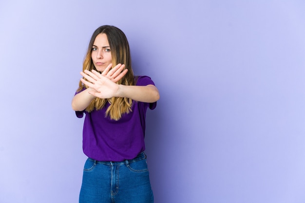 Joven mujer caucásica aislada sobre fondo púrpura de pie con la mano extendida mostrando la señal de stop, impidiéndote