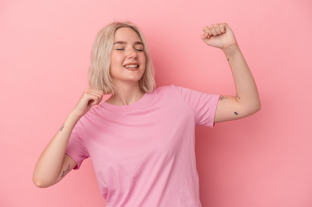 Joven mujer caucásica aislada sobre fondo rosa celebrando un día especial, salta y levanta los brazos con energía.