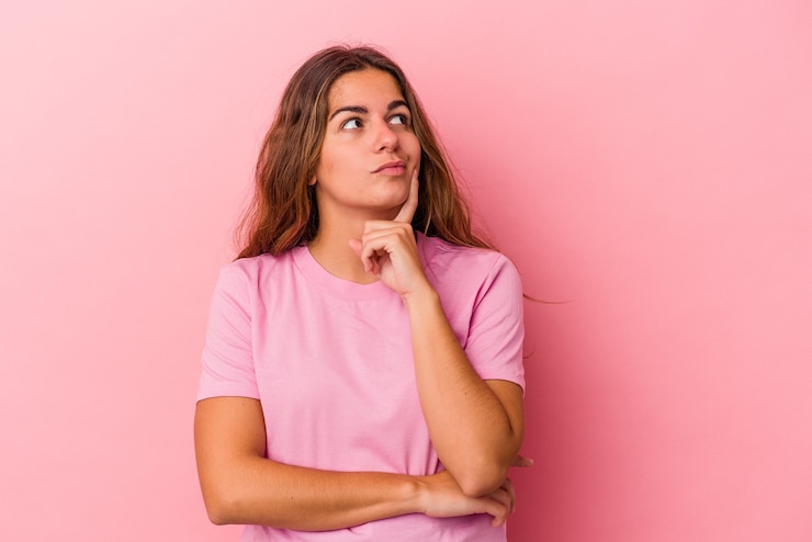 Foto joven mujer caucásica aislada sobre fondo rosa contemplando, planificando una estrategia, pensando en la forma de un negocio.
