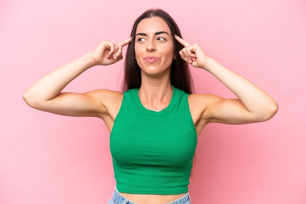 Foto joven mujer caucásica aislada sobre fondo rosa con dudas y pensamiento