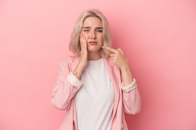 Joven mujer caucásica aislada sobre fondo rosa con un fuerte dolor de dientes, dolor de muelas.