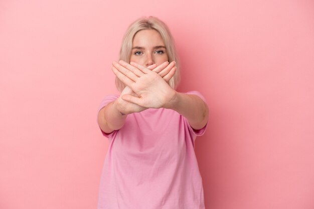 Joven mujer caucásica aislada sobre fondo rosa haciendo un gesto de negación