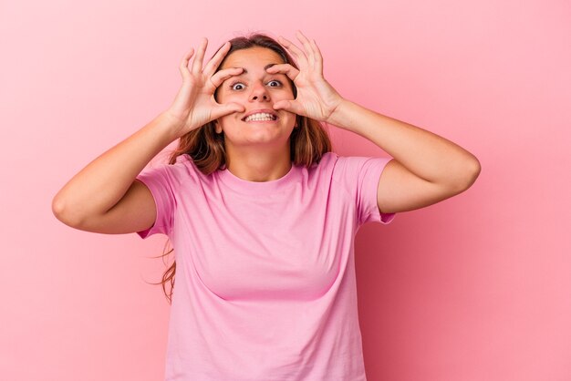 Joven mujer caucásica aislada sobre fondo rosa manteniendo los ojos abiertos para encontrar una oportunidad de éxito.