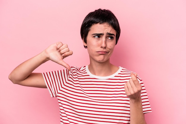 Joven mujer caucásica aislada sobre fondo rosa mostrando que no tiene dinero.