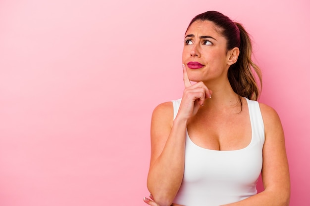 Joven mujer caucásica aislada sobre fondo rosa sonriendo y levantando el pulgar