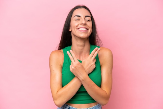 Foto joven mujer caucásica aislada sobre fondo rosa sonriendo y mostrando el signo de la victoria