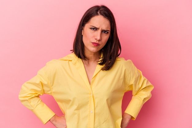 Joven mujer caucásica aislada sobre fondo rosa sopla mejillas, tiene expresión cansada. Concepto de expresión facial.