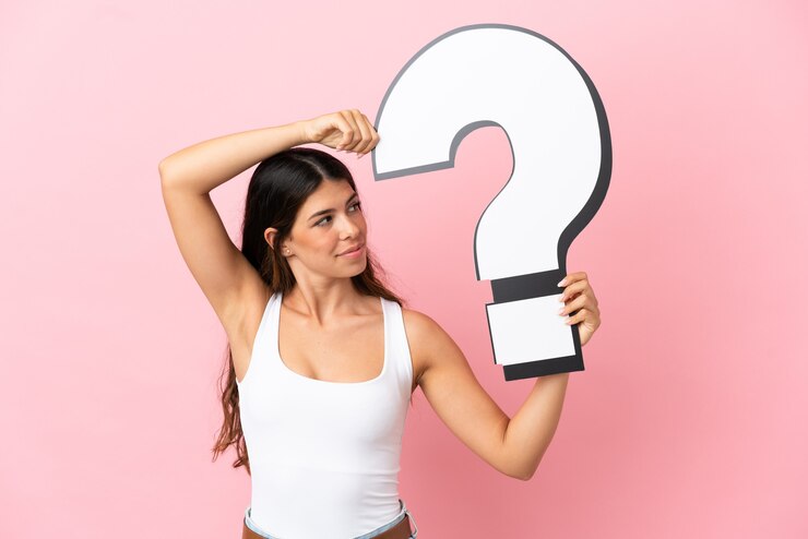 Foto joven mujer caucásica aislada sobre fondo rosa sosteniendo un icono de signo de interrogación