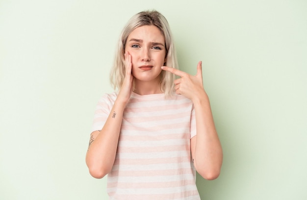 Joven mujer caucásica aislada sobre fondo verde con un fuerte dolor de dientes, dolor de muelas.