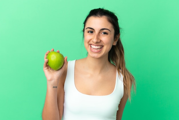 Joven mujer caucásica aislada sobre fondo verde con una manzana