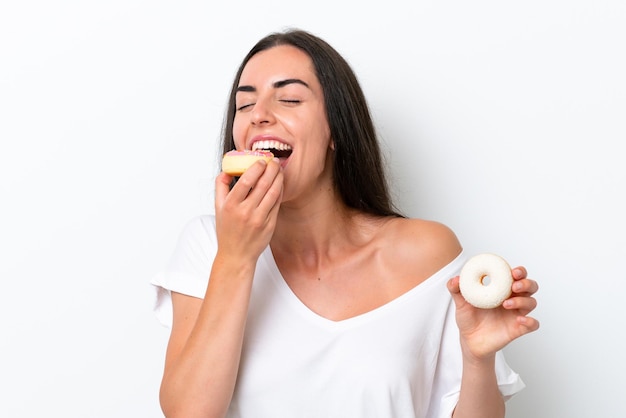 Joven mujer caucásica aislado sobre fondo blanco comiendo una rosquilla