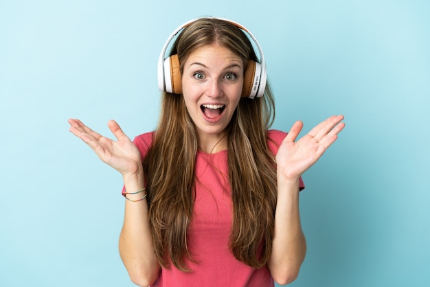 Joven mujer caucásica en azul sorprendido y escuchando música