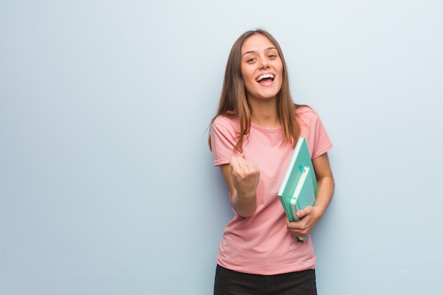 Joven mujer caucásica bastante sorprendida y conmocionada. Ella está sosteniendo libros.