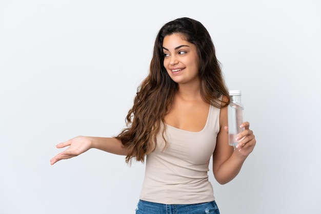 Foto joven mujer caucásica con una botella de agua aislada sobre fondo blanco con expresión de sorpresa mientras mira de lado