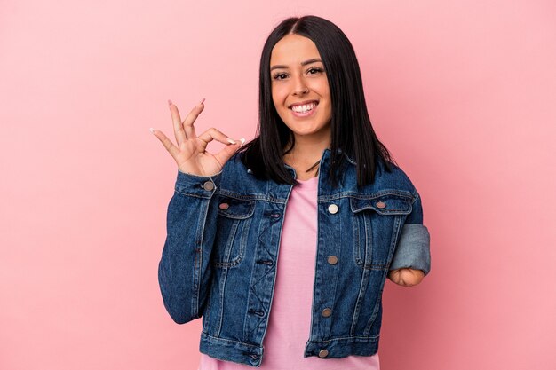 Joven mujer caucásica con un brazo aislado sobre fondo rosa alegre y confiado mostrando gesto ok.