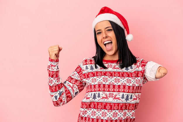 Joven mujer caucásica con un brazo celebrando la Navidad aislado sobre fondo rosa levantando el puño después de una victoria, concepto ganador.