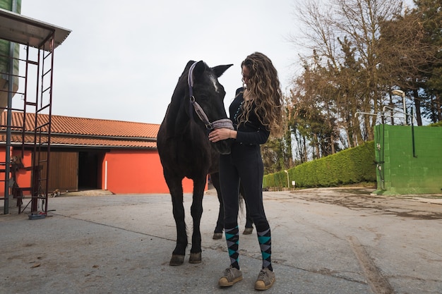 Joven mujer caucásica con un caballo en un centro ecuestre