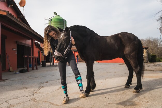 Joven mujer caucásica con un caballo en un centro ecuestre