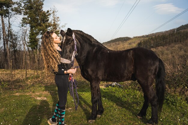 Joven mujer caucásica con un caballo en un centro ecuestre