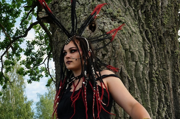 Joven mujer caucásica con cabello punk negro y rojo posando en el bosque