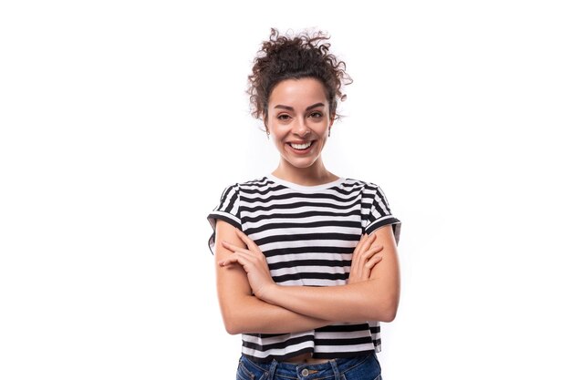 Joven mujer caucásica con cabello rizado vestido con una camiseta de verano a rayas sonriendo contra el