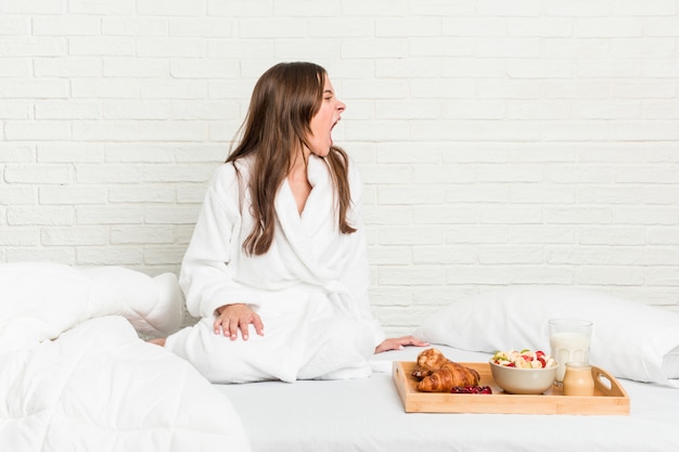 Joven mujer caucásica en la cama gritando