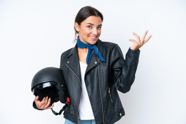 Joven mujer caucásica con un casco de motocicleta aislado de fondo azul extendiendo las manos a un lado para invitar a venir