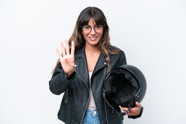 Joven mujer caucásica con un casco de motocicleta aislado sobre fondo blanco feliz y contando cuatro con los dedos