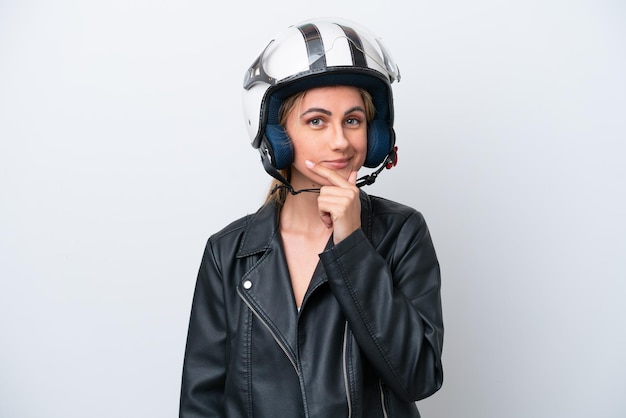 Joven mujer caucásica con un casco de motocicleta aislado sobre fondo blanco pensando