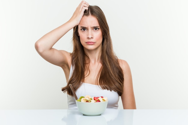 Joven mujer caucásica comiendo frutero se sorprendió, ella ha recordado reunión importante.