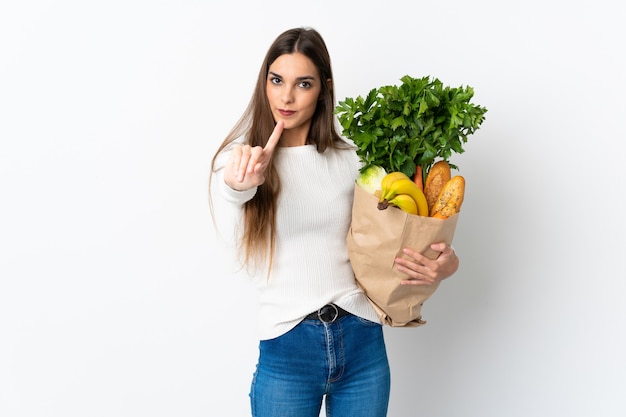 Joven mujer caucásica comprando algo de comida aislado sobre fondo blanco mostrando y levantando un dedo