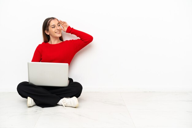 Joven mujer caucásica con una computadora portátil sentada en el suelo se ha dado cuenta de algo y tiene la intención de la solución
