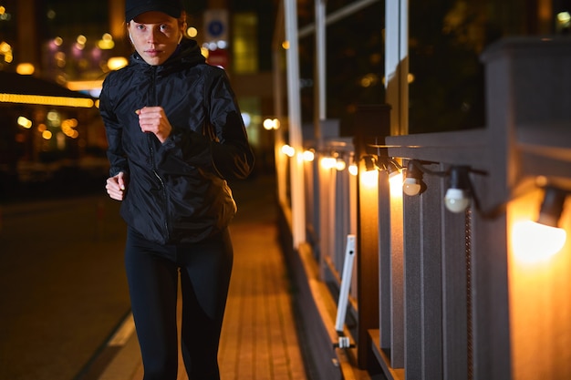 Foto joven mujer caucásica corriendo por la noche en la calle de la ciudad fitness y entrenamiento concepto de bienestar deportes ou ...