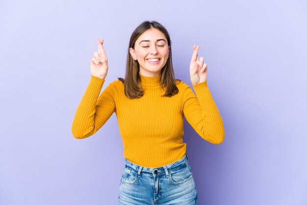 Joven mujer caucásica cruzando los dedos para tener suerte