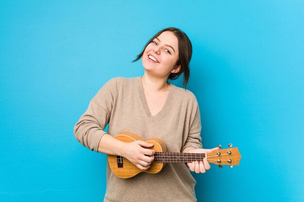 Joven mujer caucásica con curvas jugando ukelele