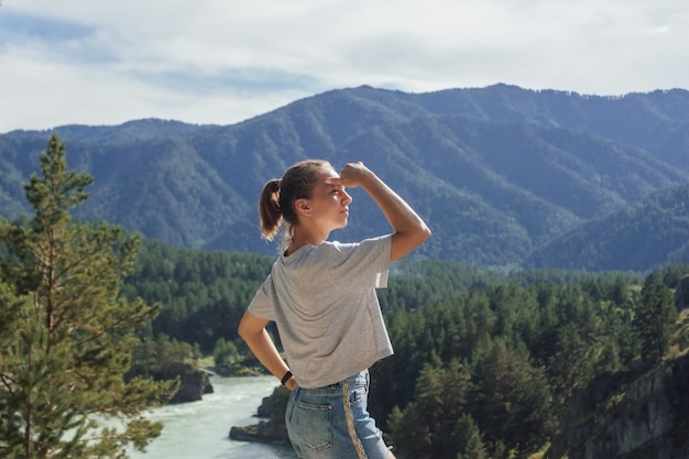 Una joven mujer caucásica delgada mira a lo lejos con el telón de fondo de un hermoso paisaje