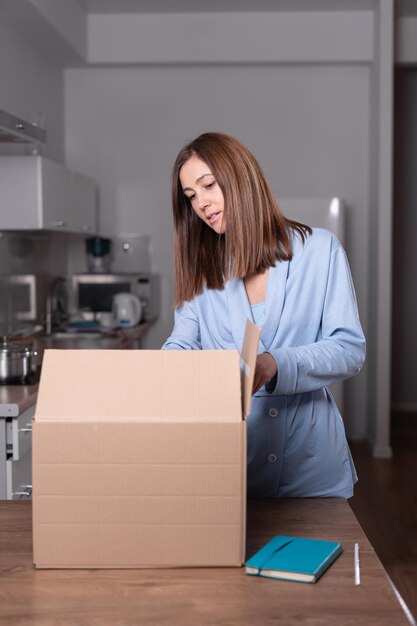 Foto joven mujer caucásica desempaca una caja en casa en un escritorio concepto de compras en línea entrega rápida espacio de copia