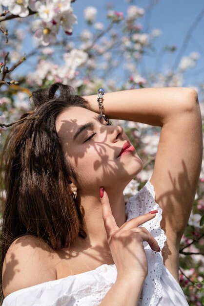 Joven mujer caucásica disfrutando del florecimiento de un manzano