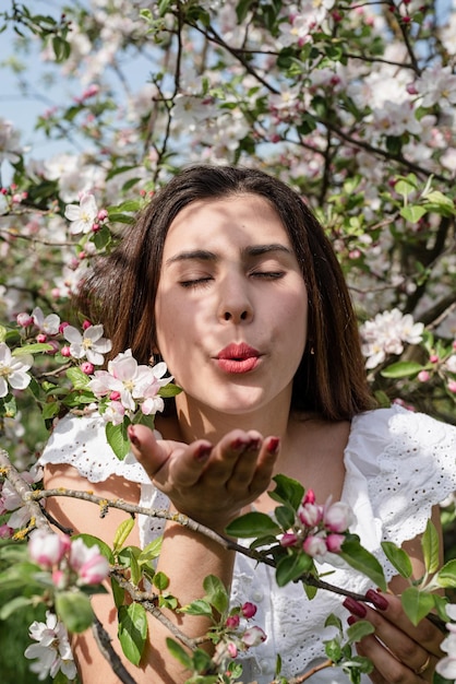 Joven mujer caucásica disfrutando del florecimiento de un manzano