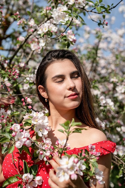 Joven mujer caucásica disfrutando del florecimiento de un manzano