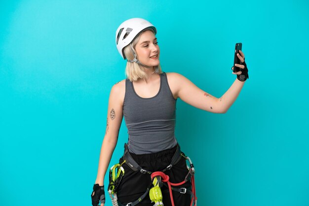 Joven mujer caucásica escalador aislada sobre fondo blanco haciendo un selfie