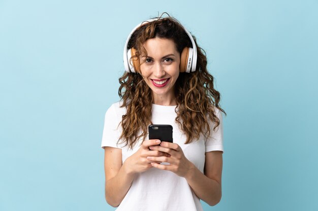 Joven mujer caucásica escuchando música con un móvil