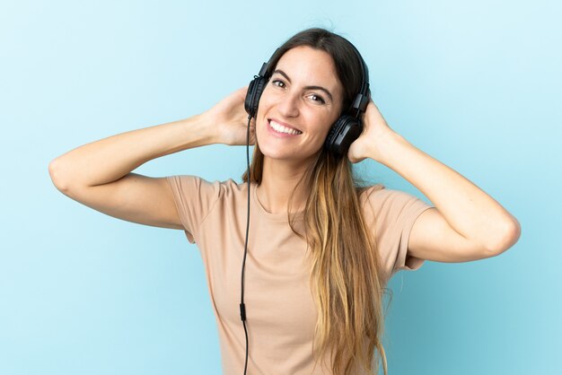 Joven mujer caucásica en escuchar música de pared azul