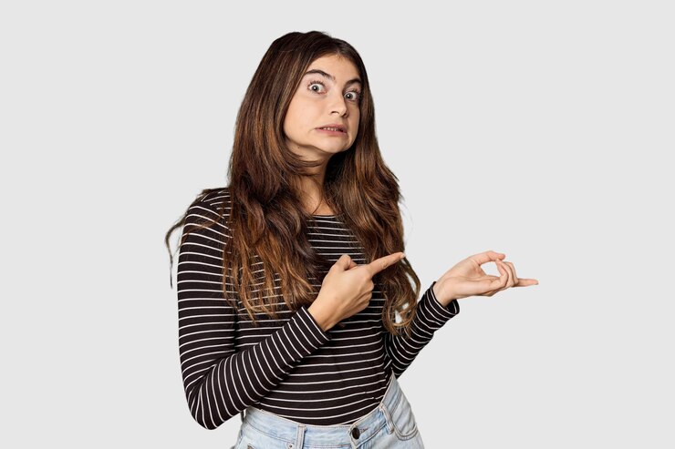Foto joven mujer caucásica en un estudio conmocionada señalando con el dedo índice a un espacio de copia