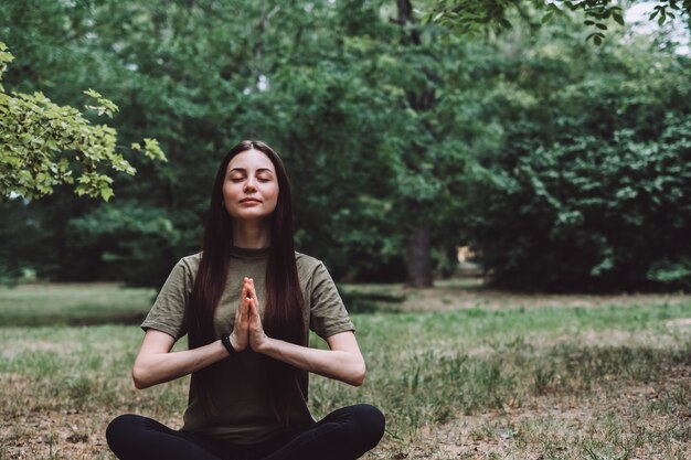 Joven mujer caucásica feliz meditando sola en la naturaleza. Estilo de vida saludable y relajaciones.