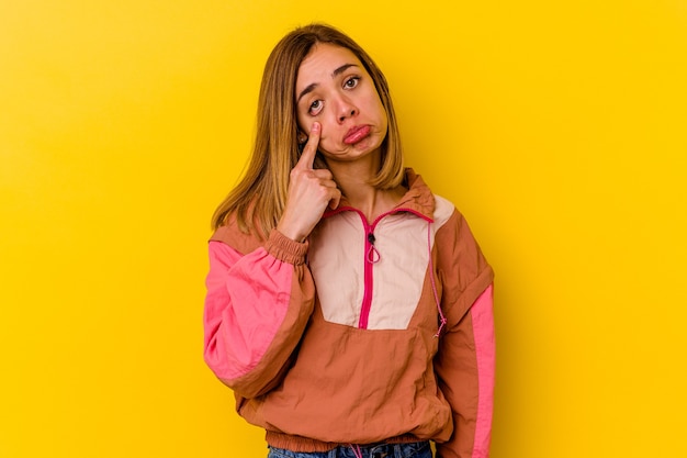 Joven mujer caucásica flaca aislada en amarillo llorando, infeliz con algo, concepto de agonía y confusión.